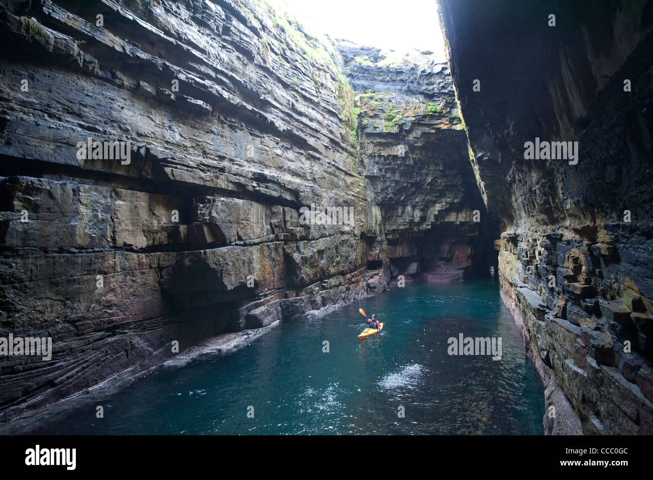 Sea kayaker in the cave beneath Downpatrick Head, County Mayo, Ireland. Stock Photo