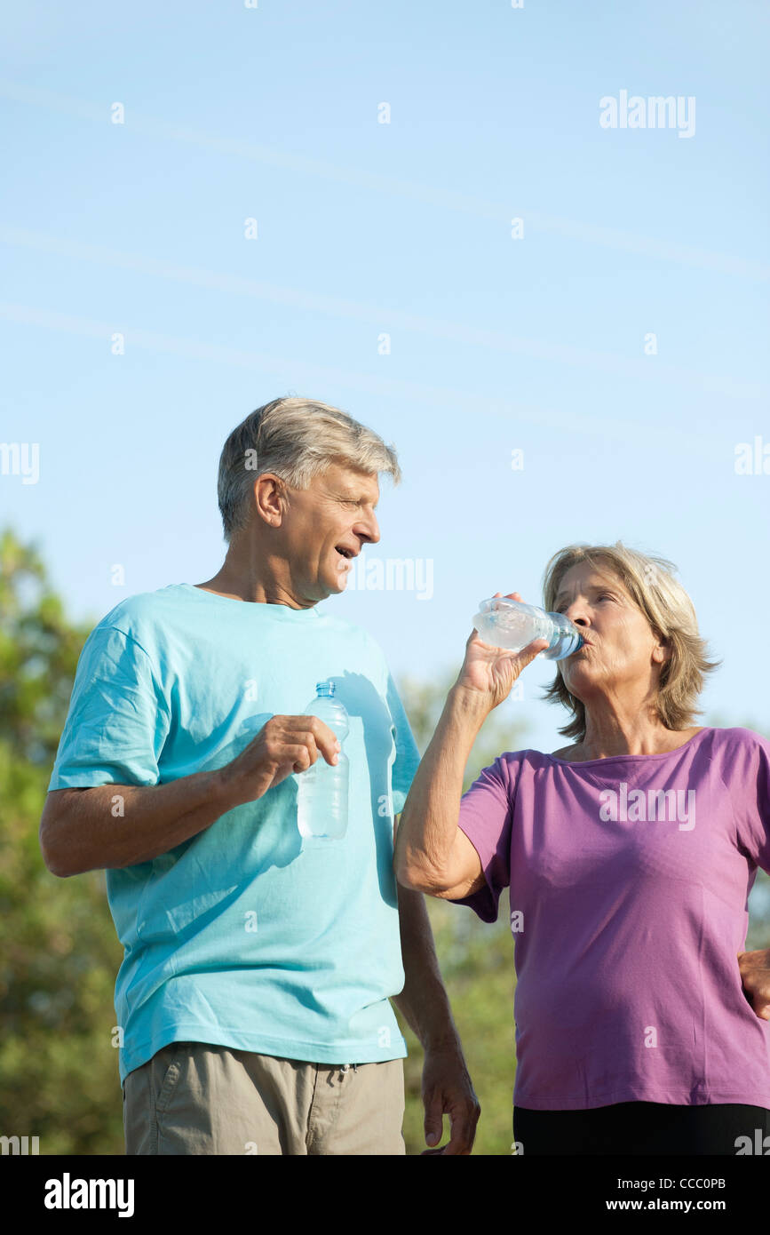 Senior couple drinking bottled water outdoors Stock Photo
