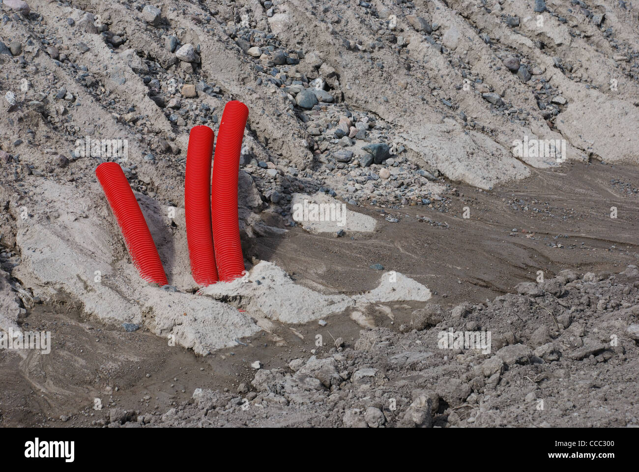 three red drainage pipe sticking out of the ground Stock Photo Alamy