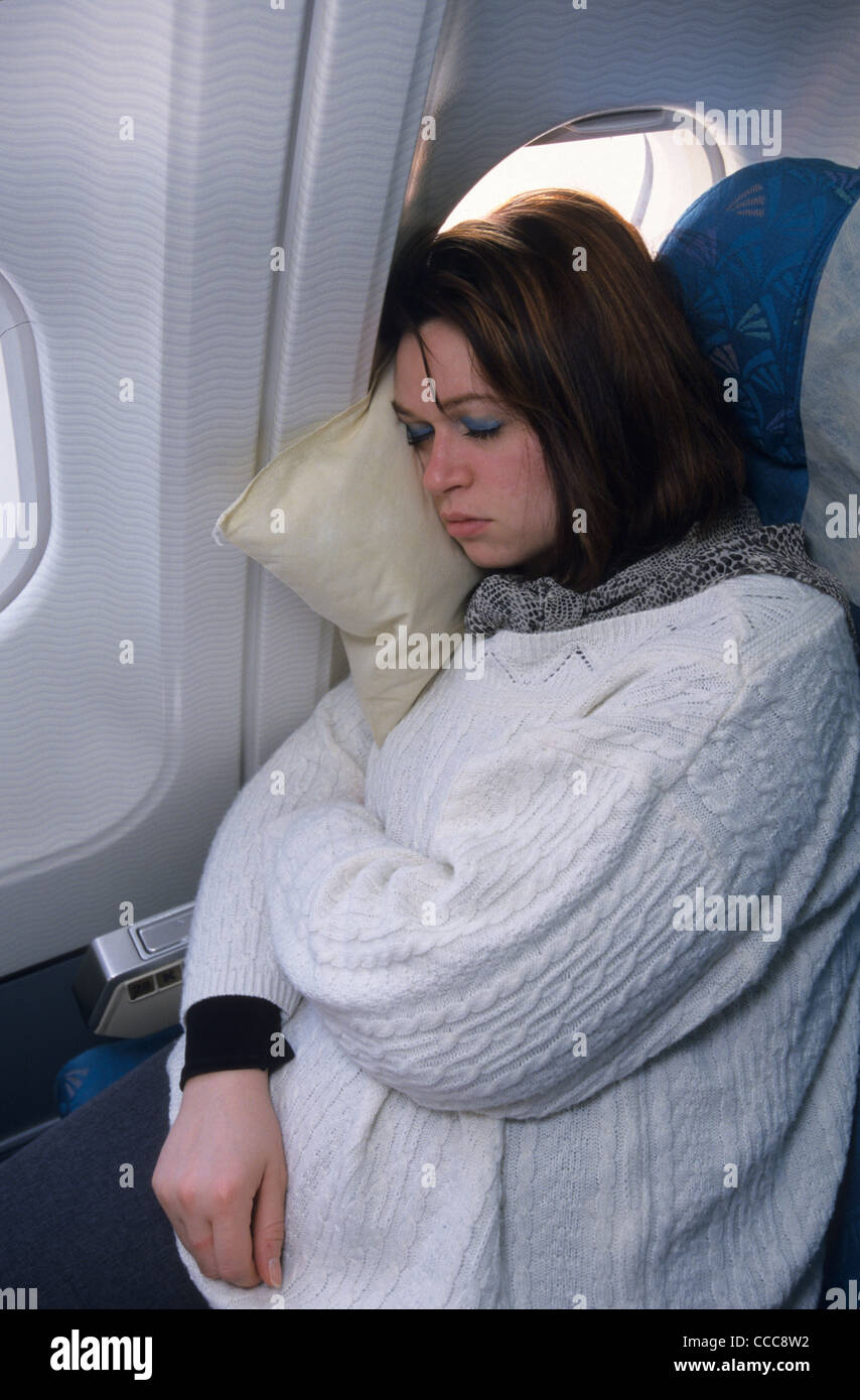 Young woman sleeping on pillow in economic class during a flight in