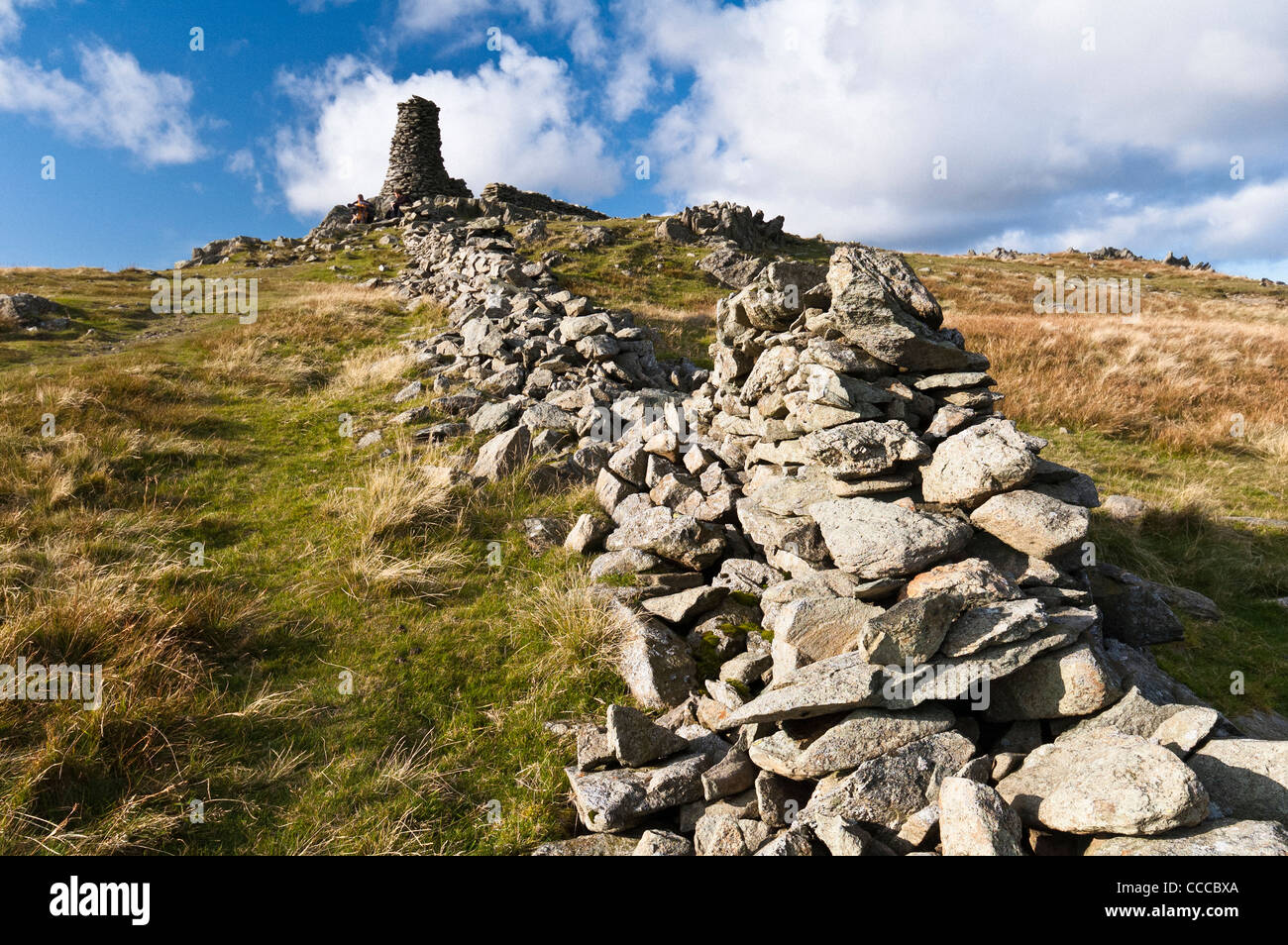 Summit of  'High Street' in the Cumbrian hills with view of a very large cairn at the end of a damaged drystone wall. Stock Photo