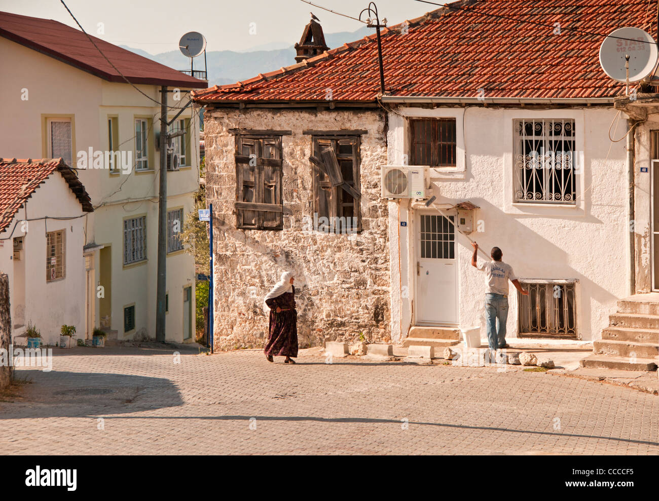 Man Whitewashing his house in the atmospheric back streets of Fethiye, Turkey, Europe Stock Photo