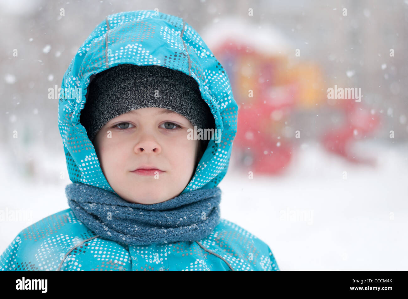 boy child portrait one eight years winter clothes blizzard snow frost down jacket hood scarf cold blue day looks right Russia Stock Photo