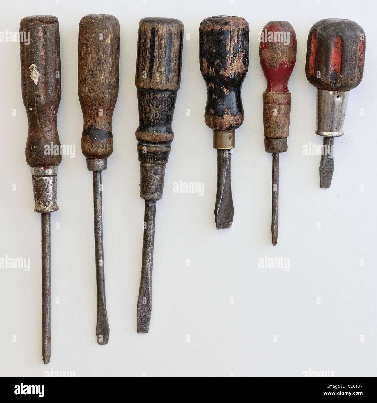 A collection of antique screwdrivers on an off white background Stock