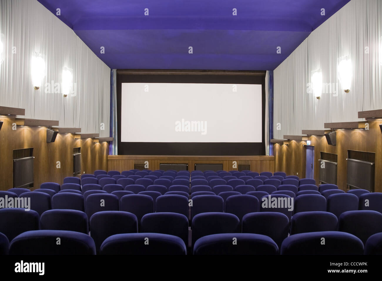 Empty cinema auditorium with line of chairs and projection screen ...