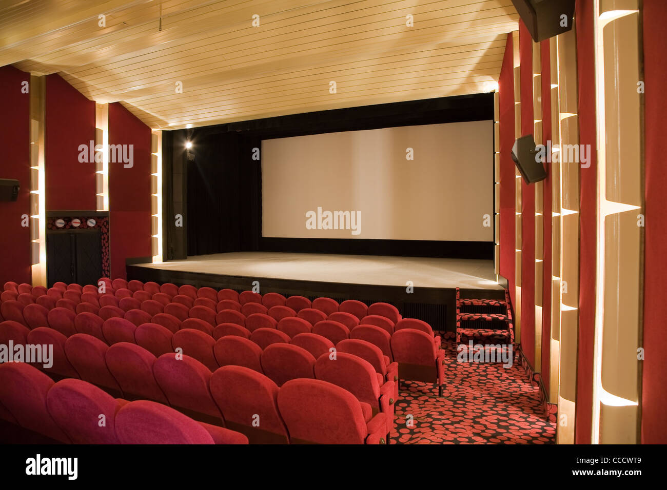 Empty cinema auditorium with line of chairs and projection screen ...