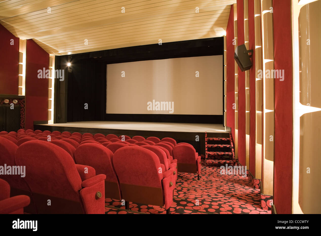 Empty cinema auditorium with line of chairs and projection screen ...