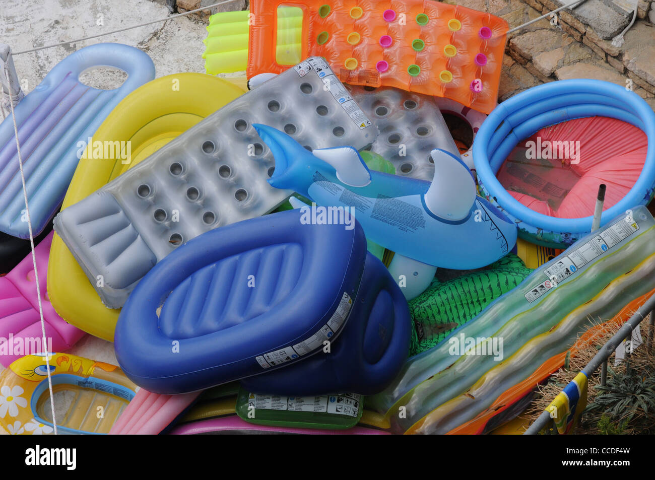 Plastic inflatable shark, pool, lounger, bright colours, blue, yellow, orange, red, grey Stock Photo