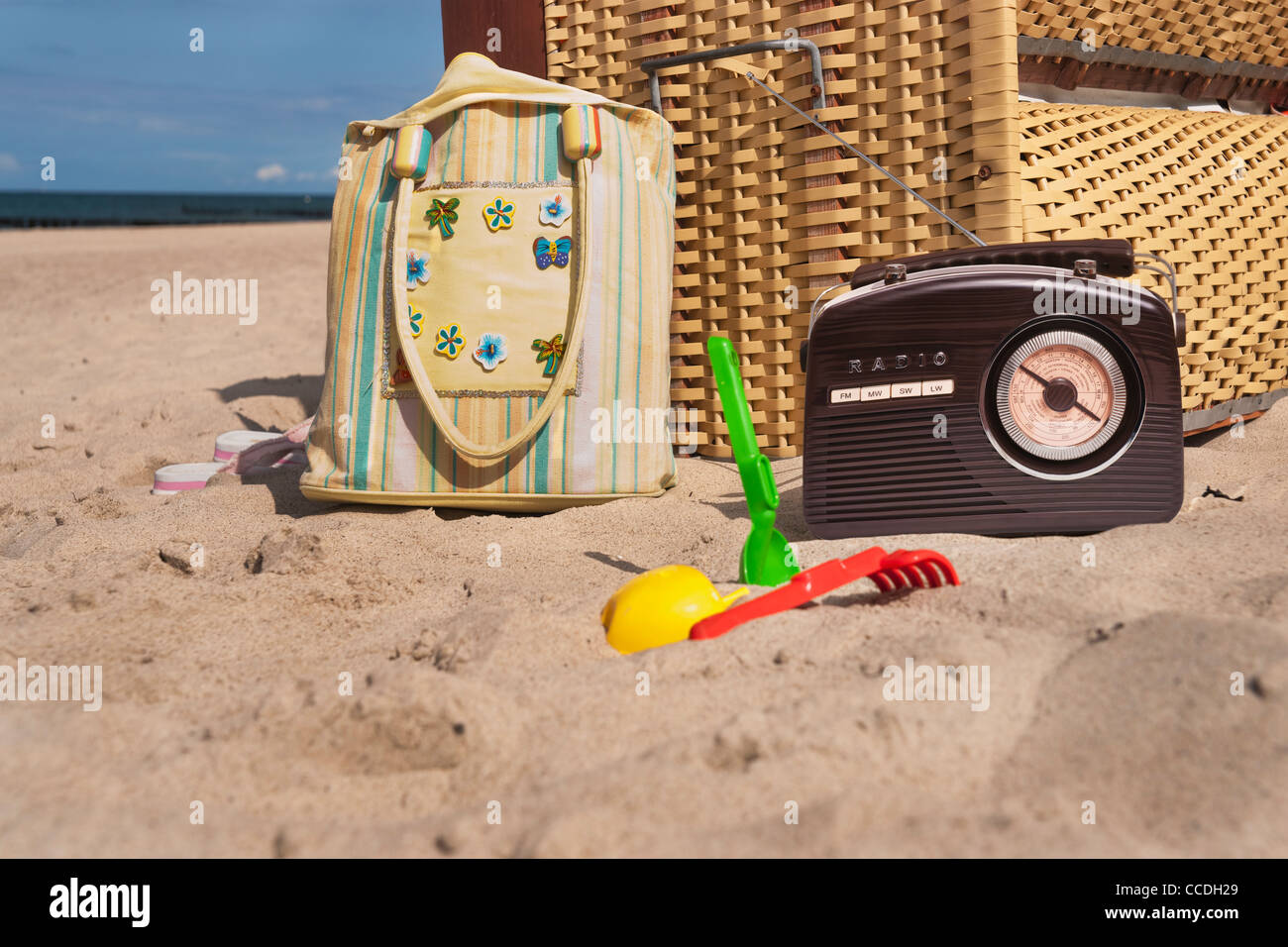 a beach chair, alongside are a radio, a beach bag and beach toys Stock Photo