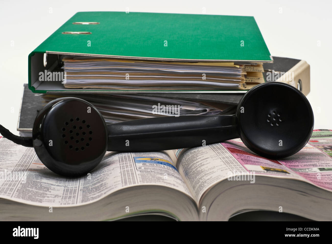 Detail photo of an old telephone receiver, lying on a phone book,  alongside are files Stock Photo