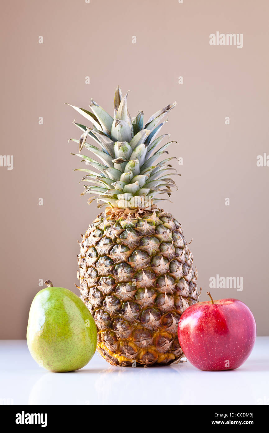 Trio of fruits pineapple, pear and apple on white with taupe brown
