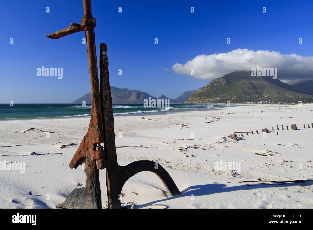 Shipwreck with rudder on the beach with a mountain backdrop Stock Photo