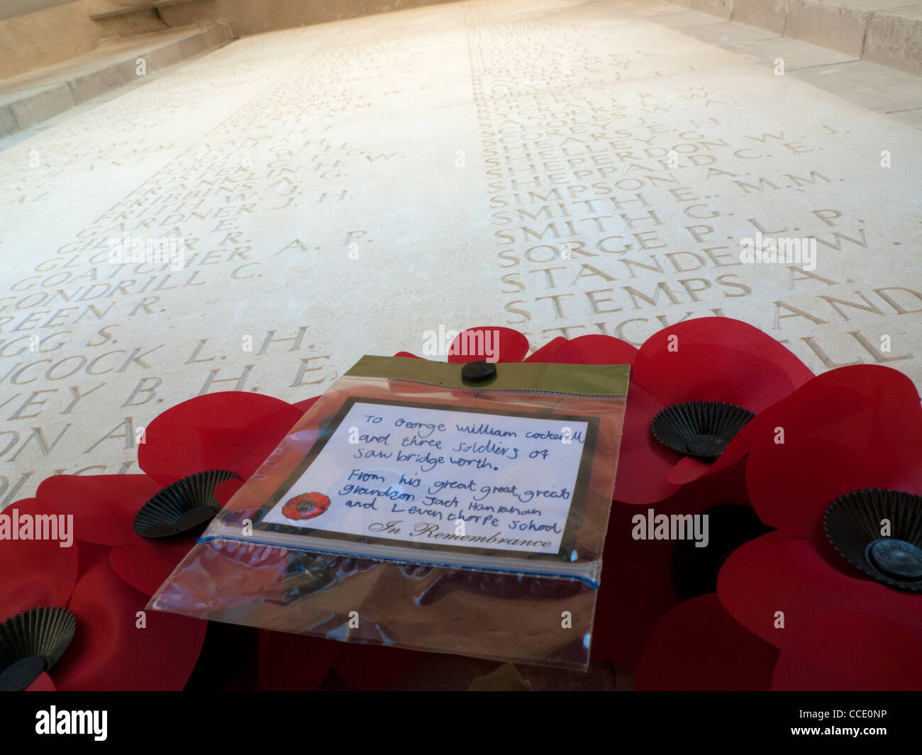 Poppy wreath with message from schololchildren at Pozieres British WW1 Cemetery, and names of missing on walls, Somme, France Stock Photo