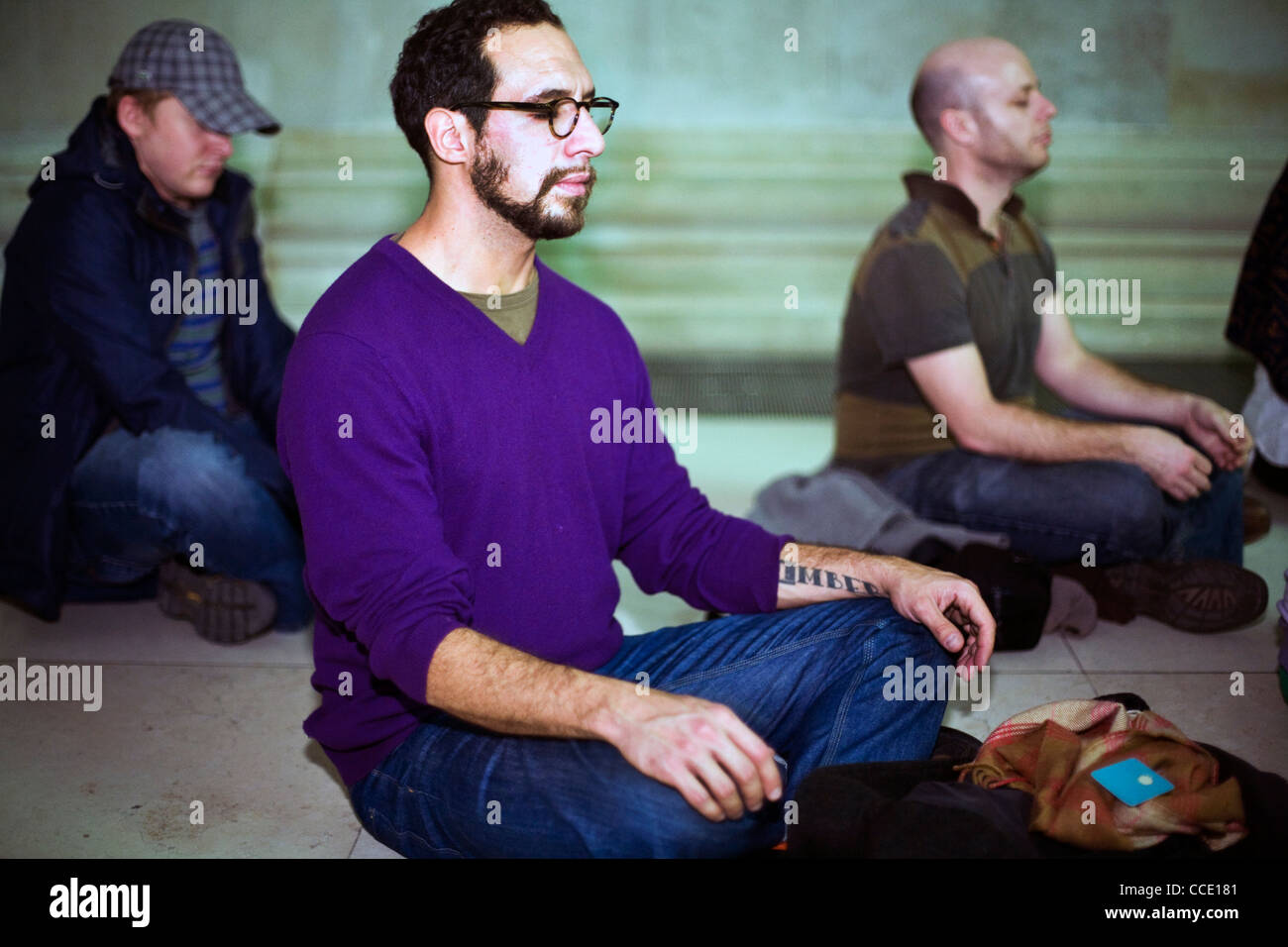 Men silently meditate as part of a meditation flash mob in the Great Court of the British Museum Stock Photo