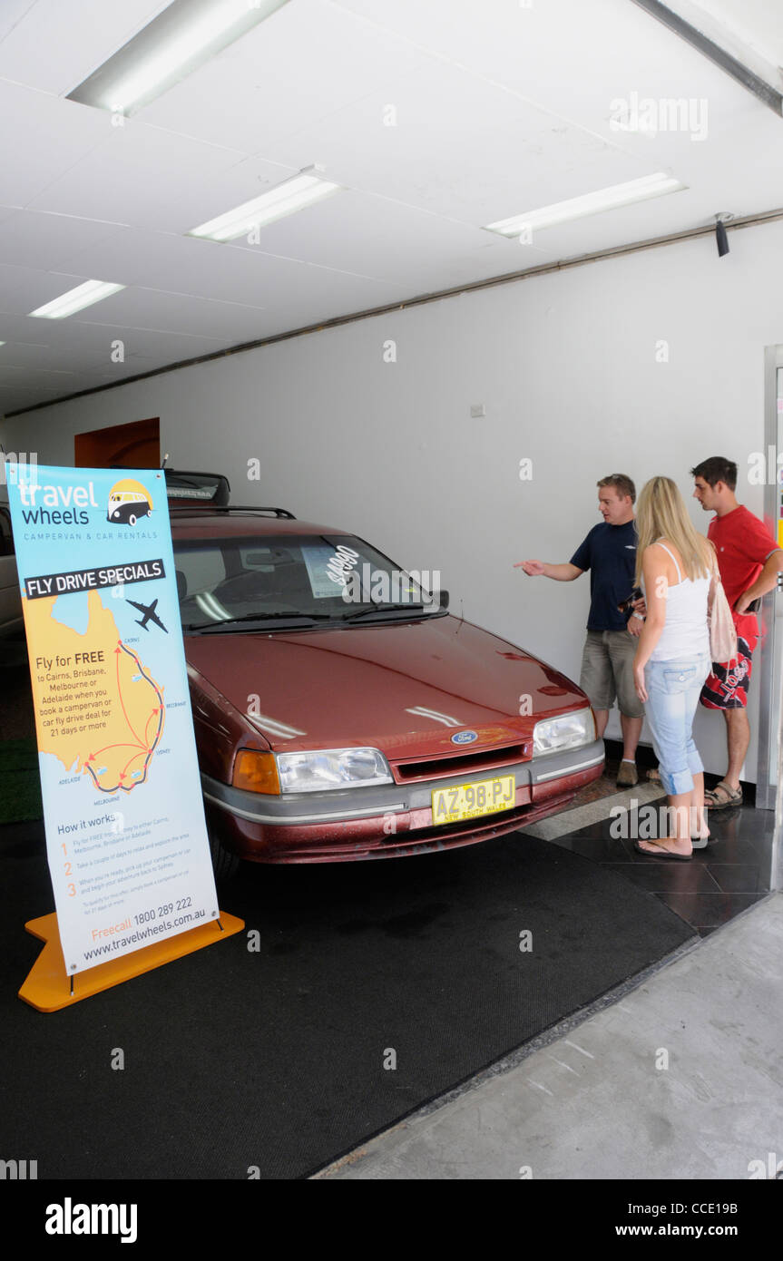 A car dealer showing a  young couple on a Backpacking tour interested in buying  a cheap car at one of the car dealerships in Kings Cross area of Stock Photo