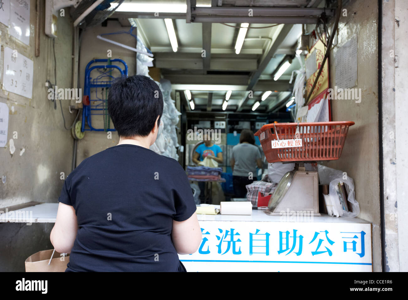 woman waiting at entrance to small chinese laundry service aberdeen hong kong hksar china asia
