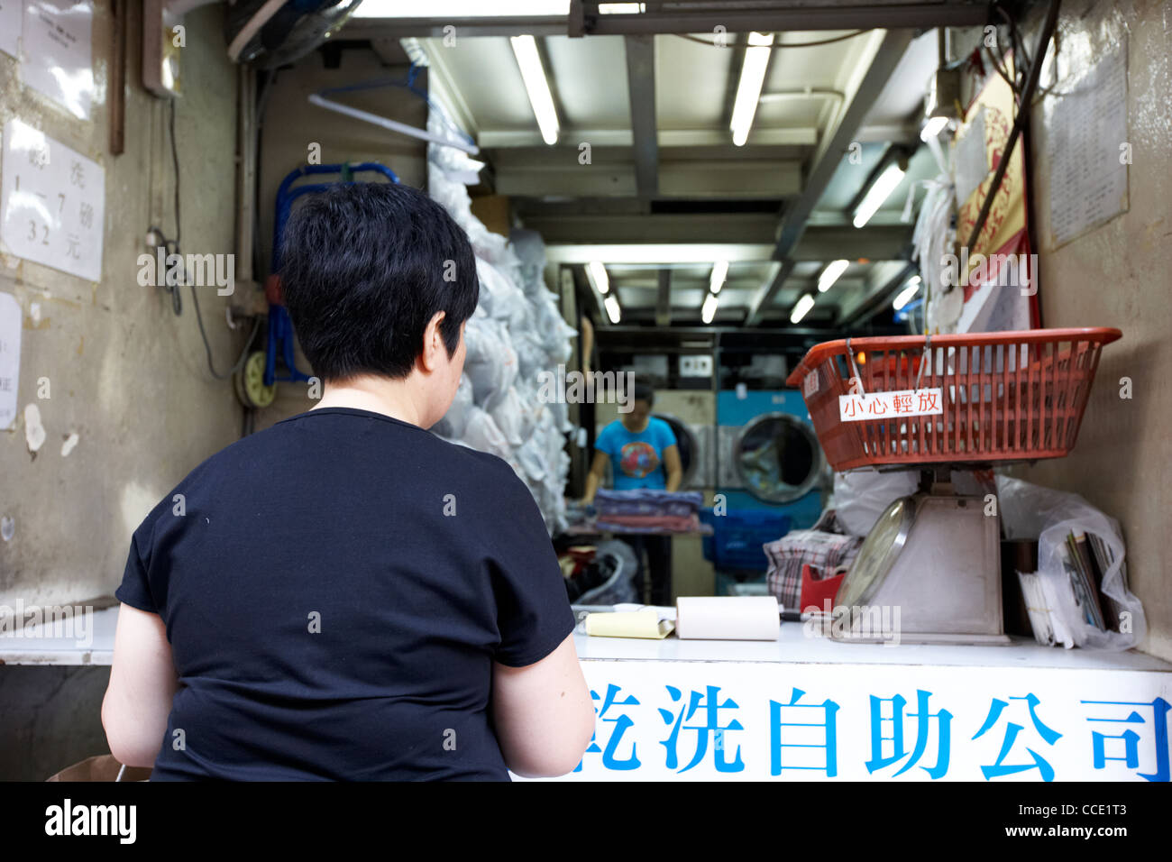woman waiting at entrance to small chinese laundry service aberdeen hong kong hksar china asia