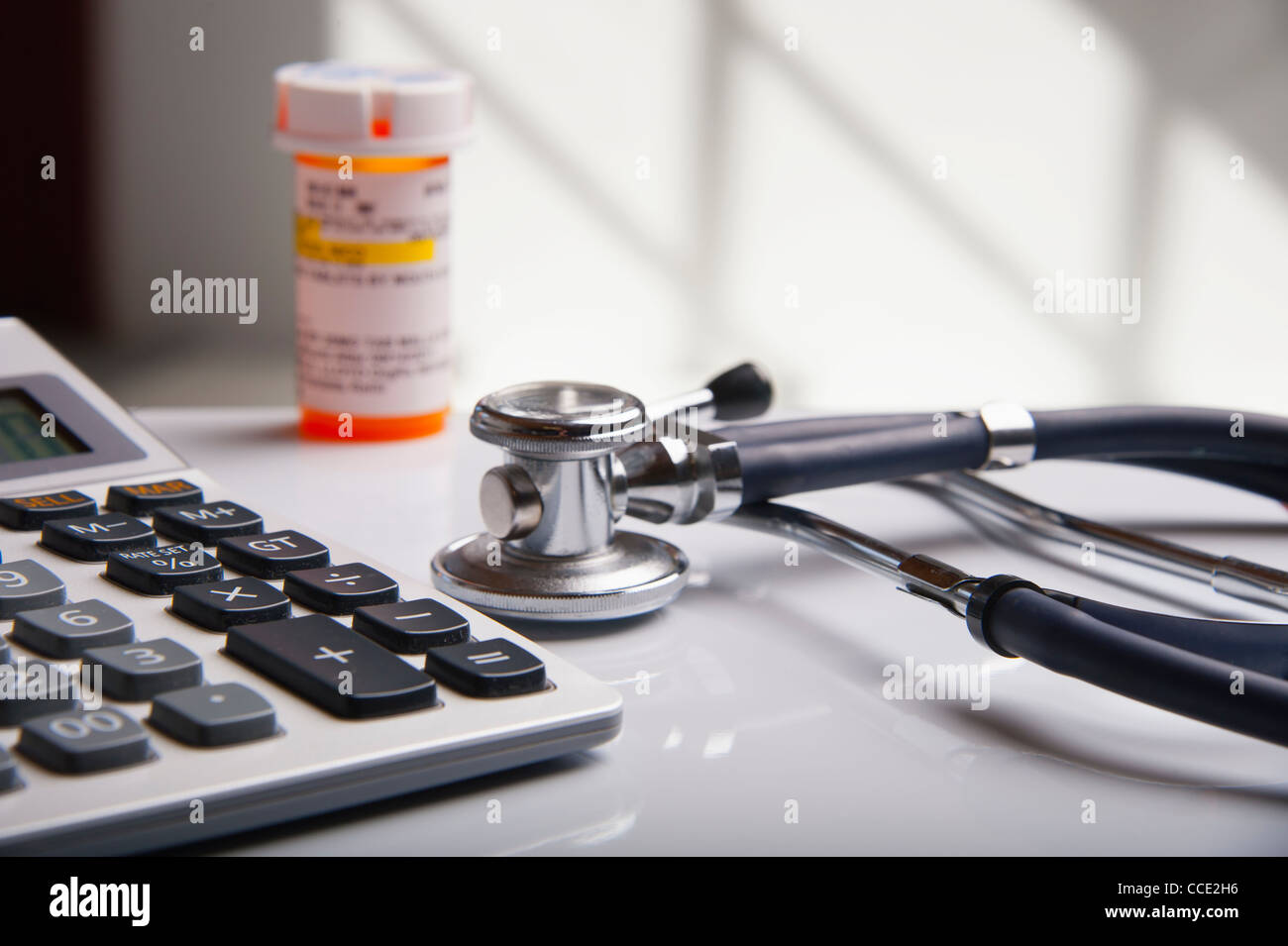 Doctor's desk with calculator, stethoscope and bottle of tablets Stock