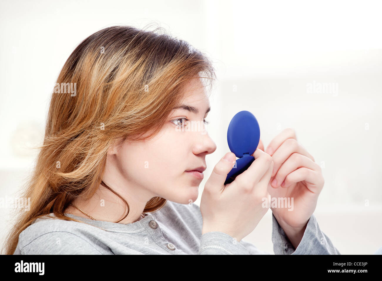 teenager girl looking in the mirror and checks pimples on face Stock Photo