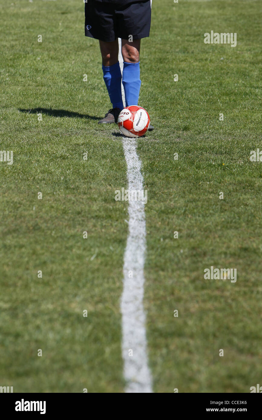 A footballers legs and a football on the centre line. Stock Photo
