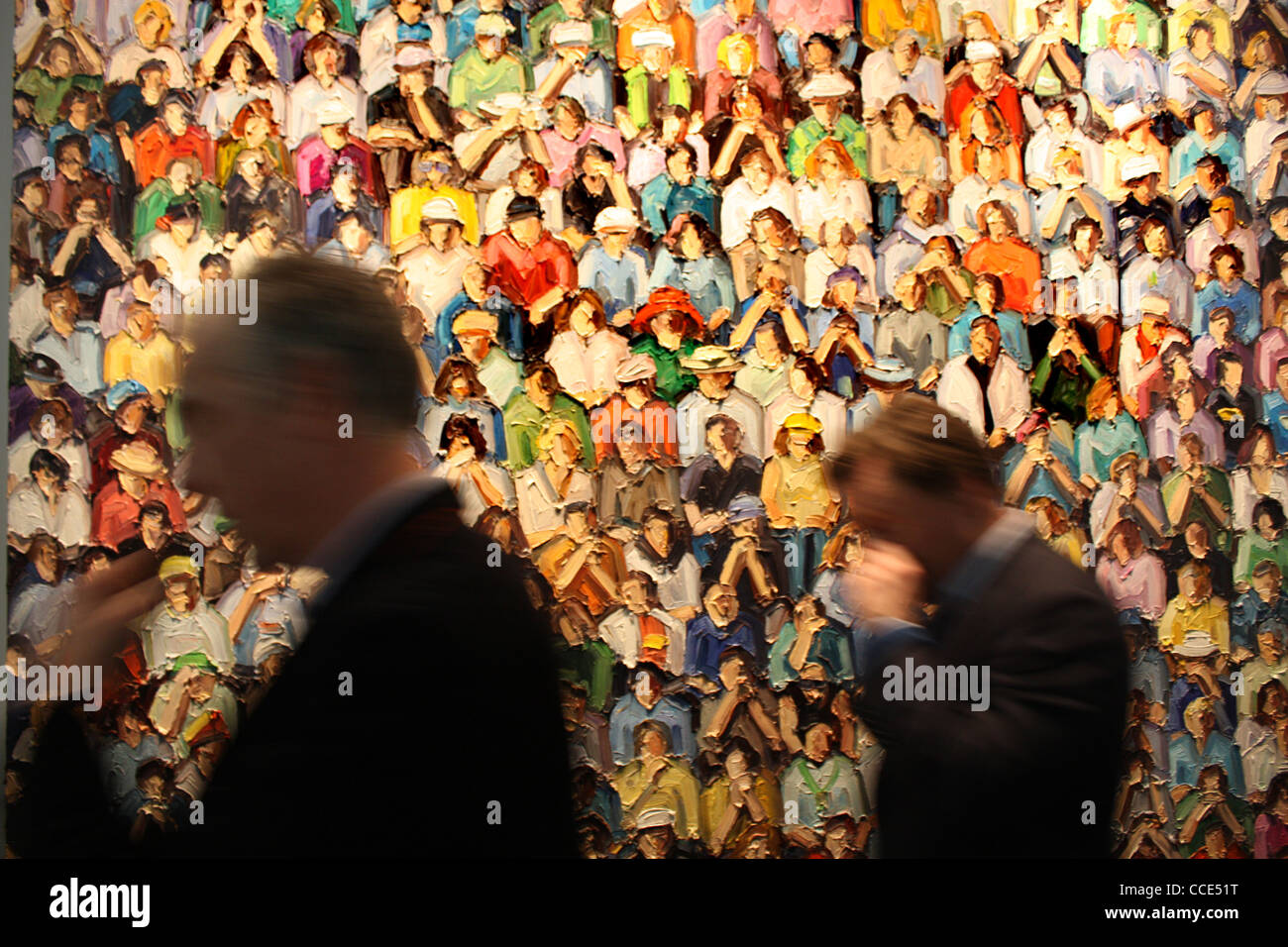 two suited men walking past a painting of a crowd, detail of Stadion by Ralph Fleck, 2011 Stock Photo