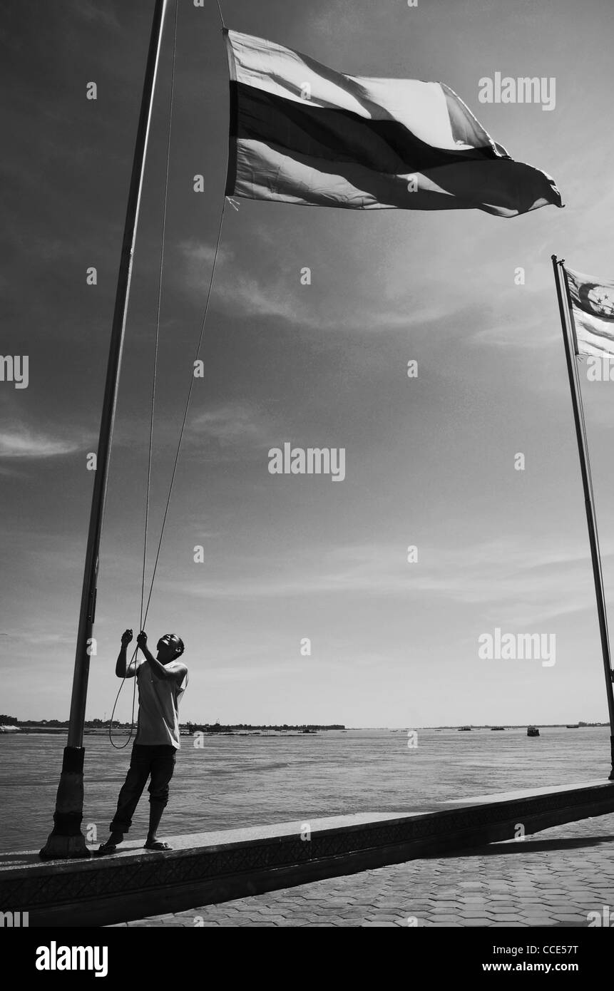 A man raises flags at the riverside in Phnom Penh, Cambodia Stock Photo