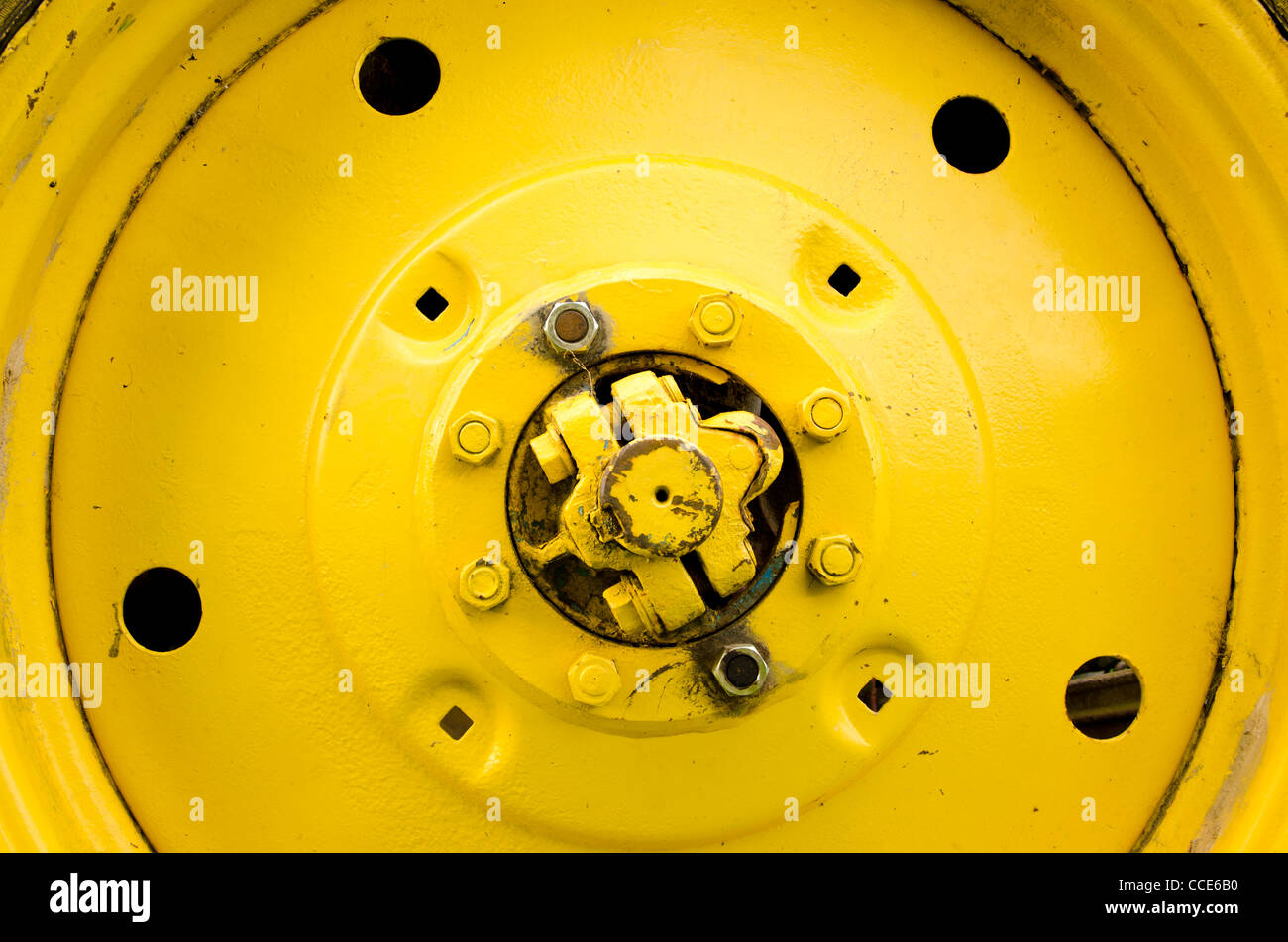Yellow tractor wheel closeup details bolts nuts holes Stock Photo