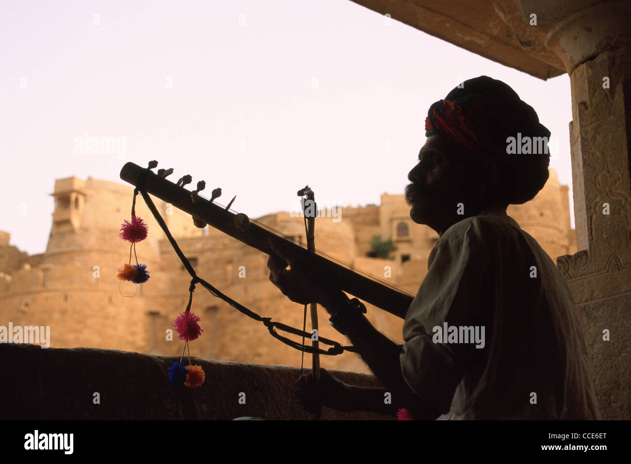 Minstrel ( "bhopa" in hindi) playing music in front of an historical monument ( the Jaisalmer fort) ( India) Stock Photo