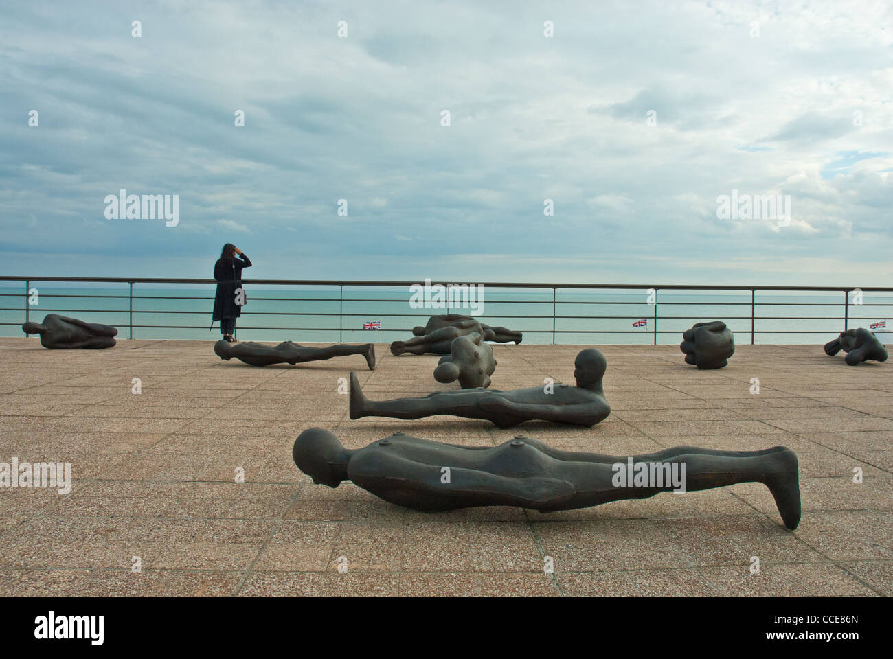 Antony Gormley  'Critical Mass' sculpted bodies, De La Warr pavilion roof, and woman in black gazing to sea and storm clouds. Stock Photo