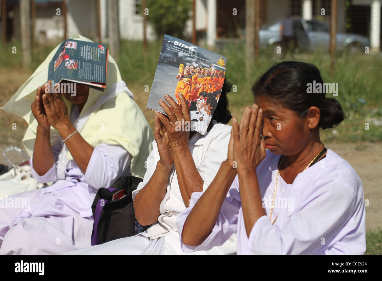 Thai female lay Buddhists gesture in respect towards Buddhist monks who