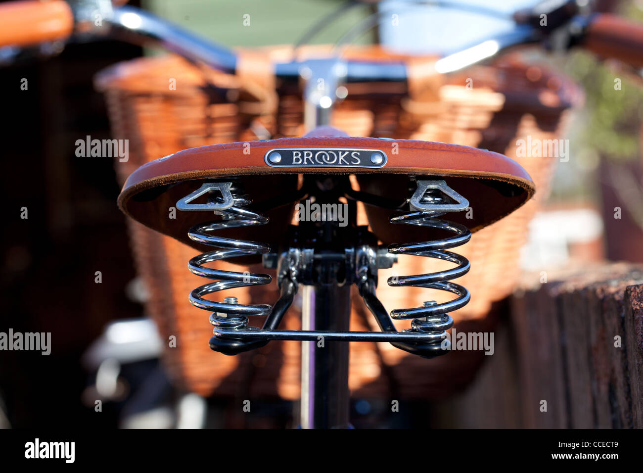 rear view of a classic leather Brooks bike Saddle showing the chrome springs and basket in the distance. Stock Photo