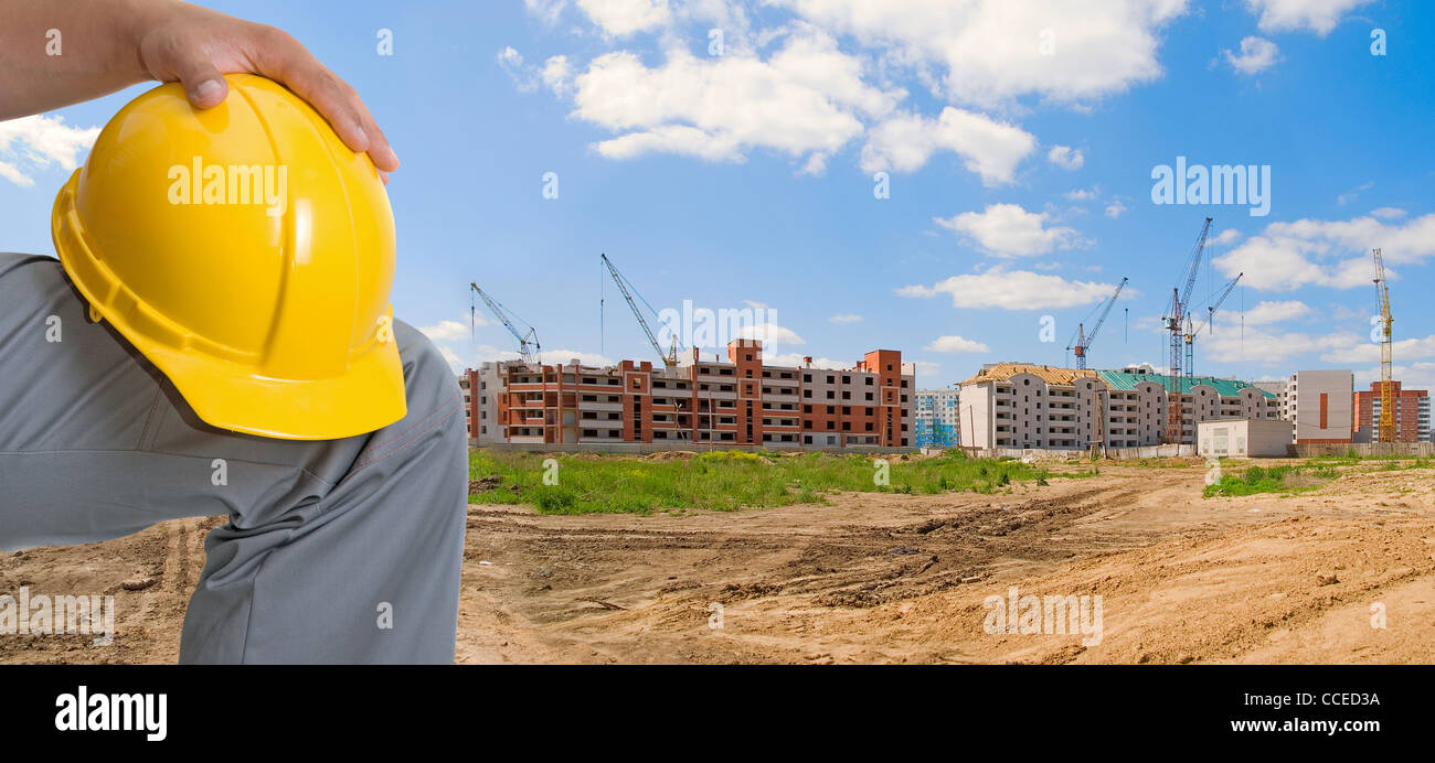 Closeup of yellow helmet at builder hands on building background Stock Photo