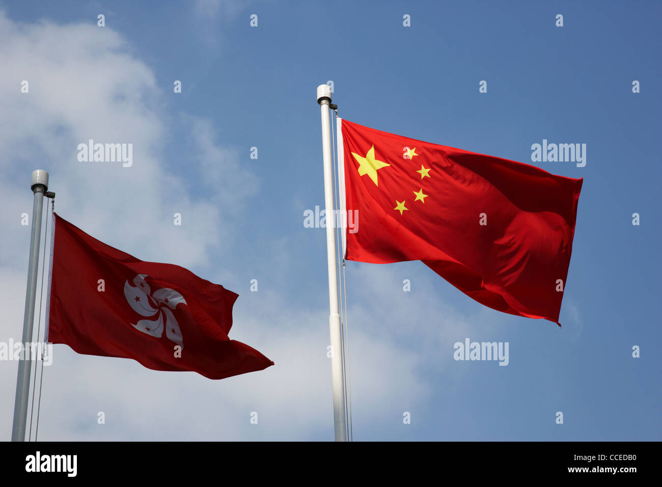 hong kong and chinese flags flying with hong kong flag in shade Stock