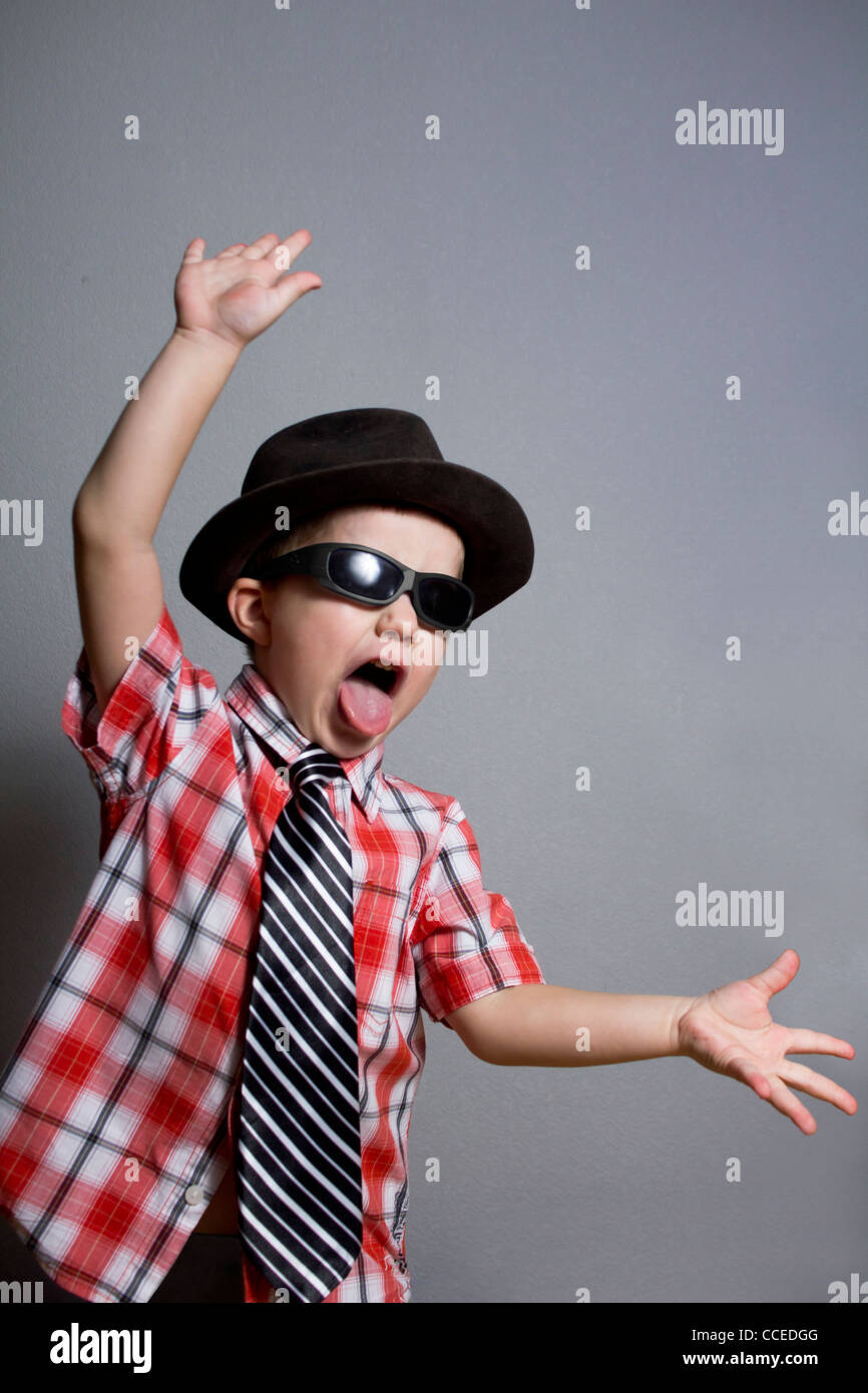 The boy in a hat and black glasses on a gray background Stock Photo