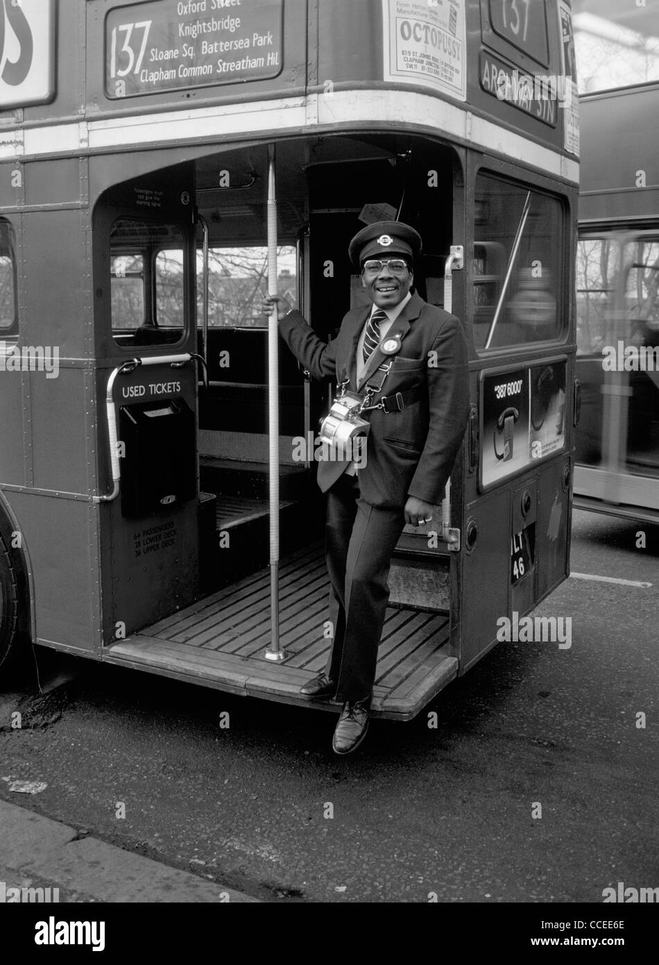 A West Indian London Bus Conductor standing on the platform of a London Transport Routemaster Bus, grinning at the photographer. Stock Photo
