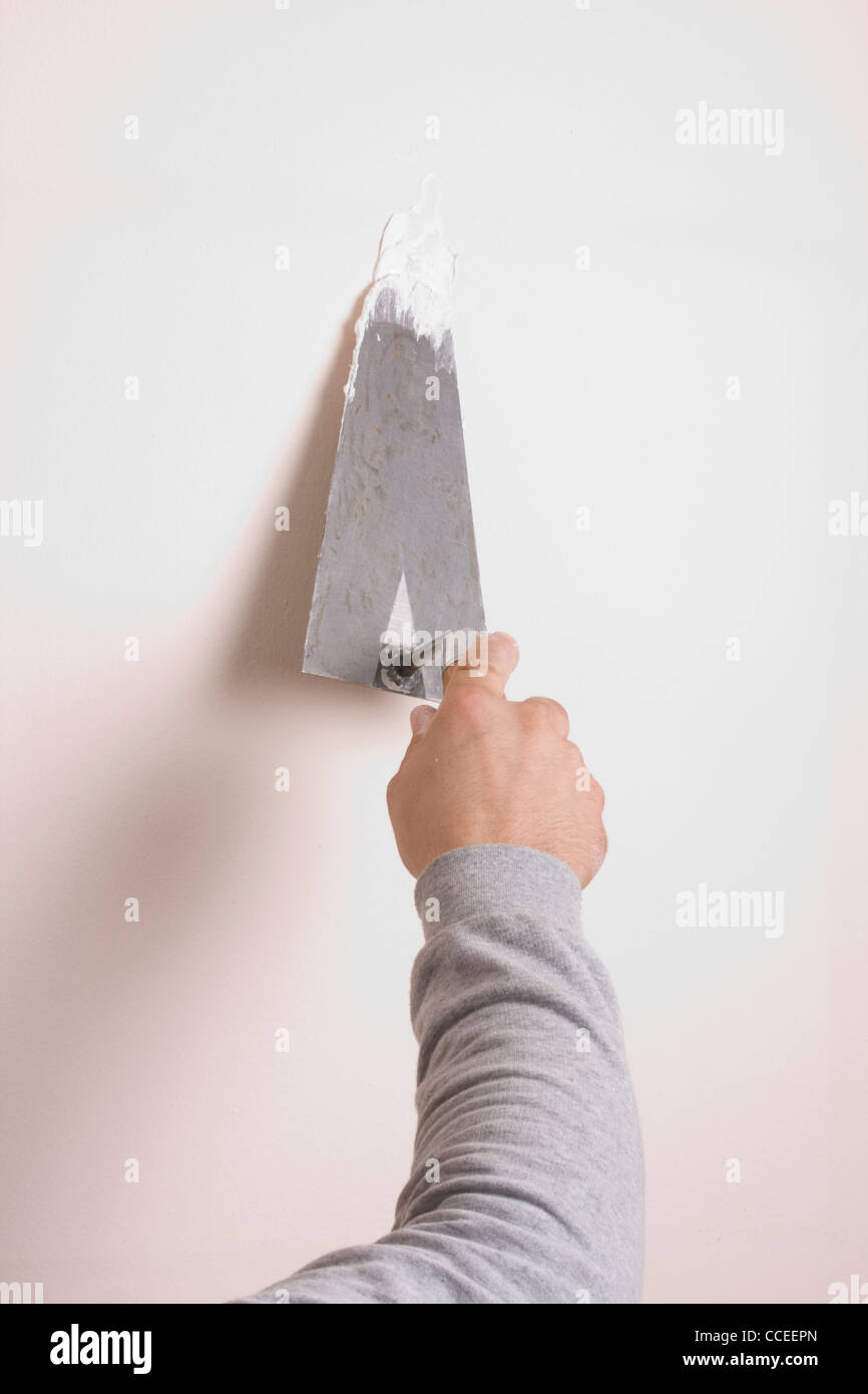 Putty Knife with Paste to Repair Wall Damage Stock Photo