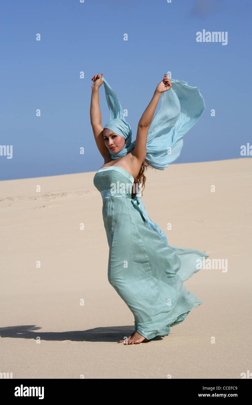 Indonesian Girl in a Turquoise Dress Posing on Sand Dunes, Fuerteventura, Canary Islands, Spain. Stock Photo