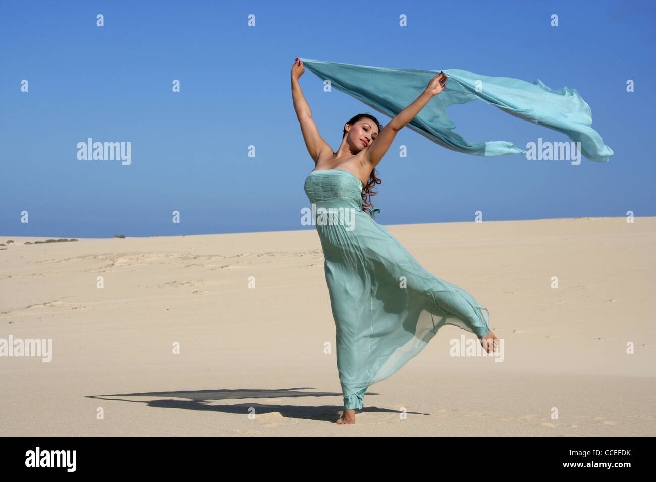 Indonesian Girl in a Turquoise Dress Posing on Sand Dunes, Fuerteventura, Canary Islands, Spain. Stock Photo