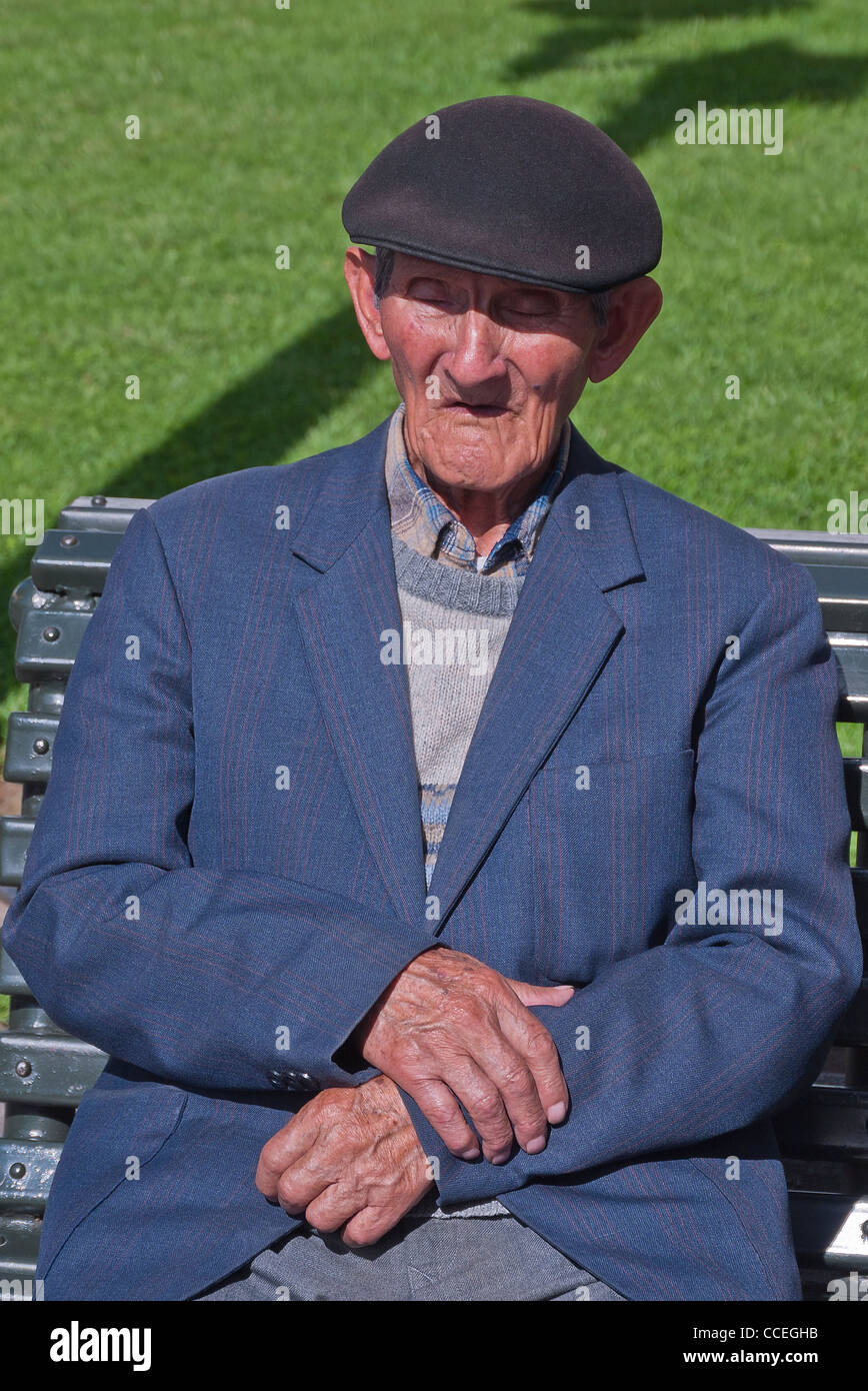 A 70-80 year old man with his eyes closed  and hands crossed naps while sitting in Plaza de la Independencia in Quito, Ecuador. Stock Photo