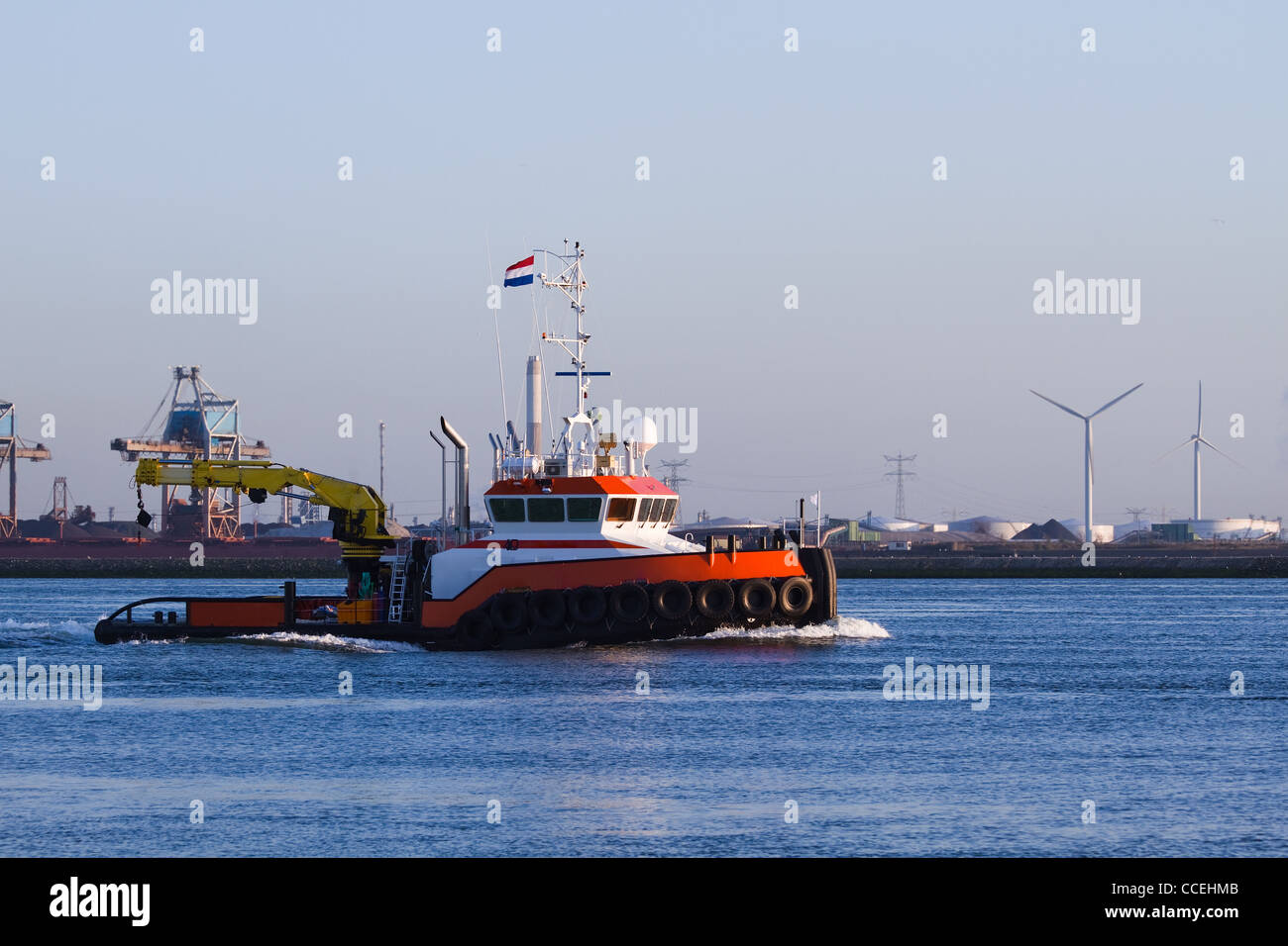 Tugboat with crane passing by on the river in evening light - industrial background Stock Photo