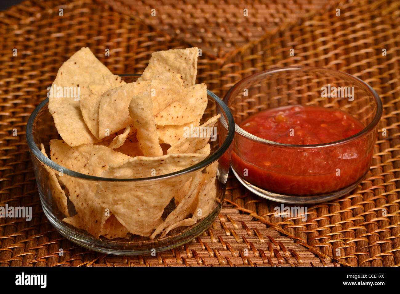 Chips and Salsa in glass bowl on a wicker style mat. Stock Photo