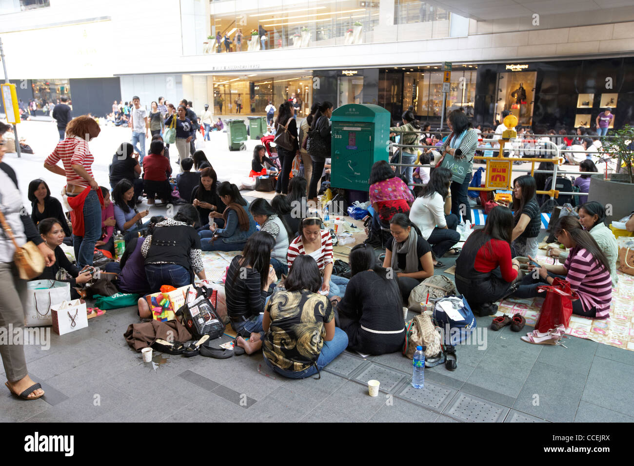 filipino and chinese domestic staff on their day off sitting in groups on the pavement chater road hong kong hksar china asia Stock Photo