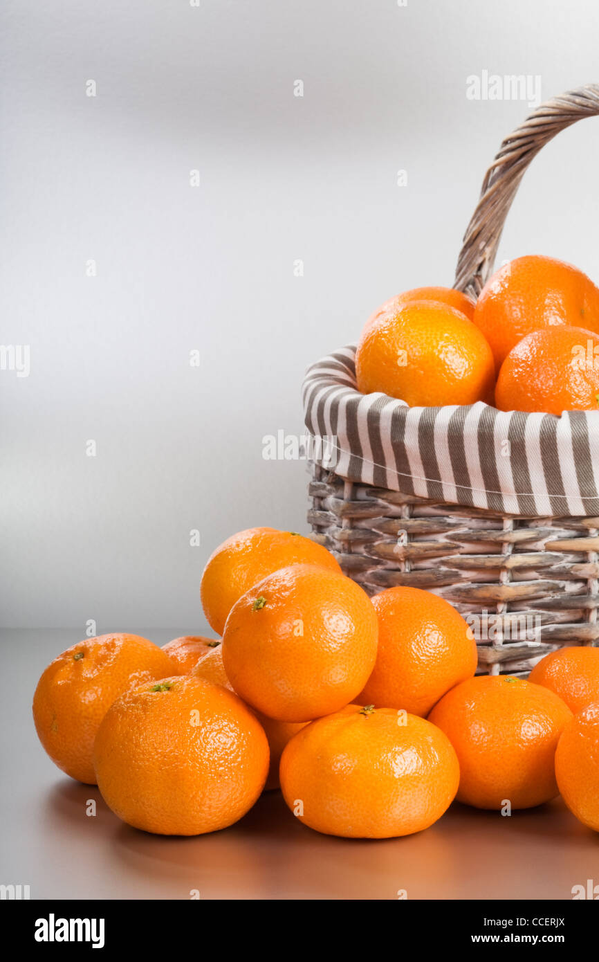 Basket and stack of fresh tangerines on silver background Stock Photo