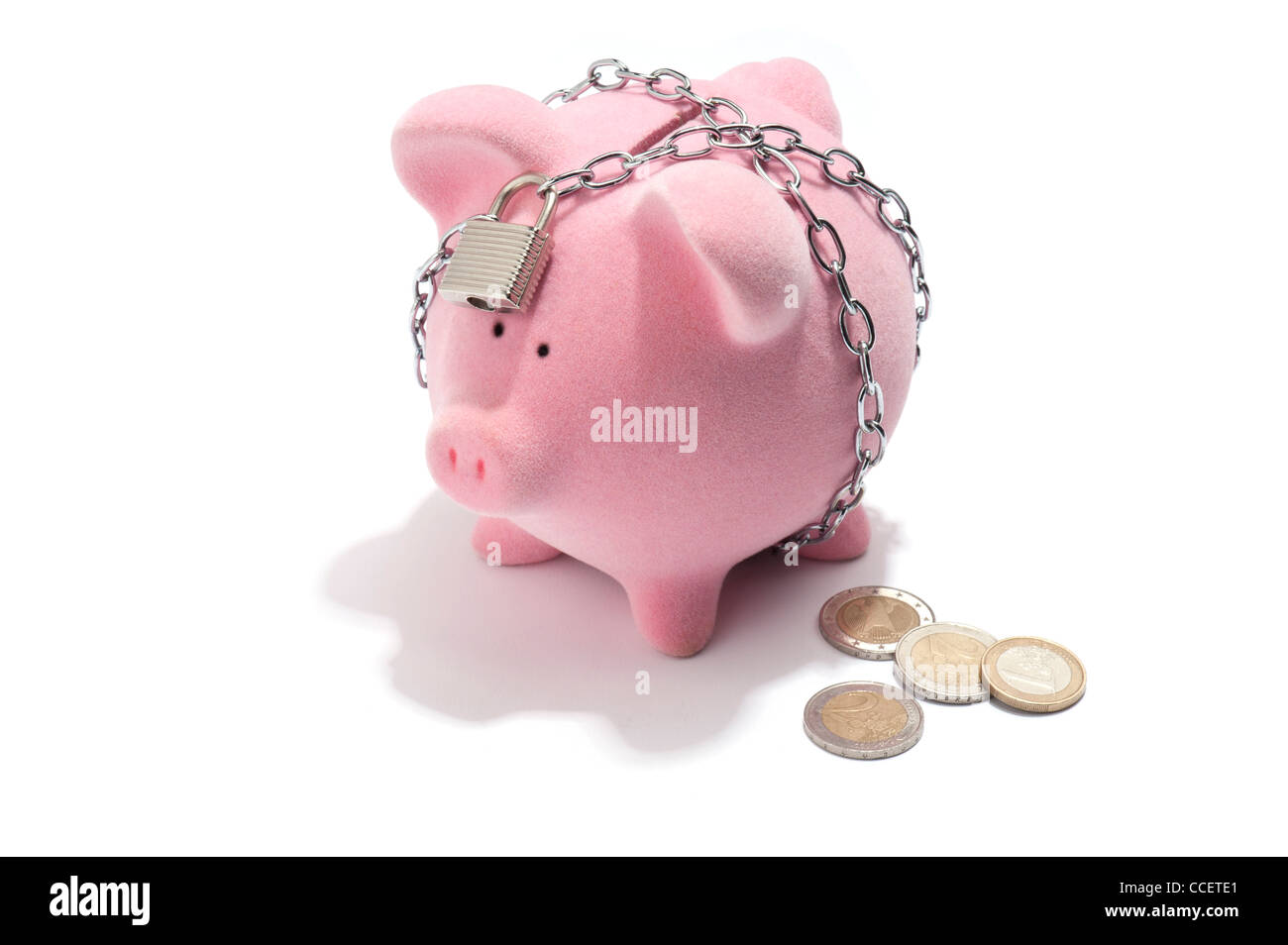 A chained and padlocked piggy bank with Euro coins next to it Stock Photo