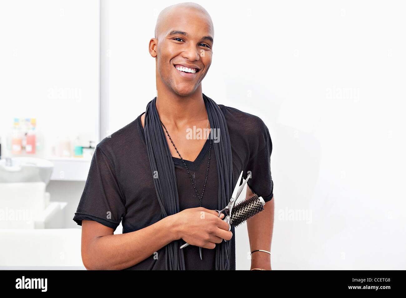 Portrait of happy male stylist holding hairbrush and scissors Stock Photo