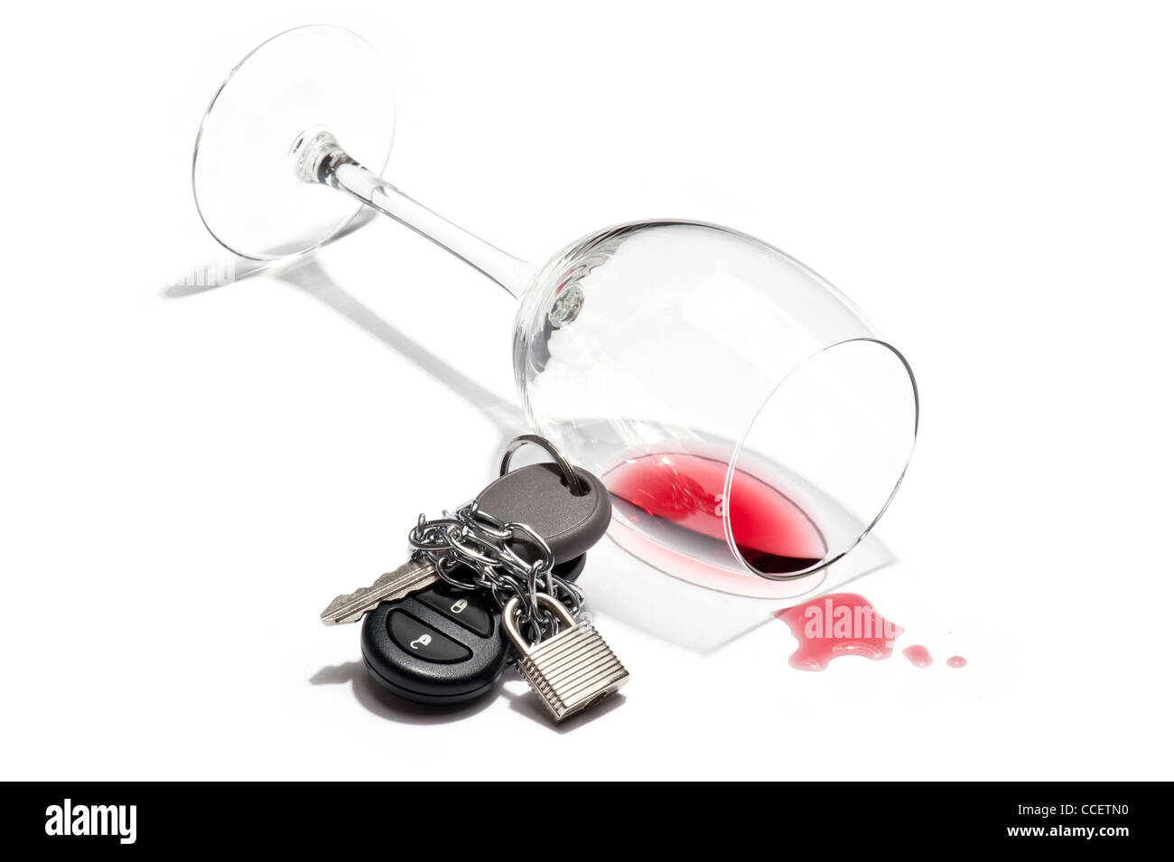 An knocked over glass of wine and a car key chained and padlocked Stock