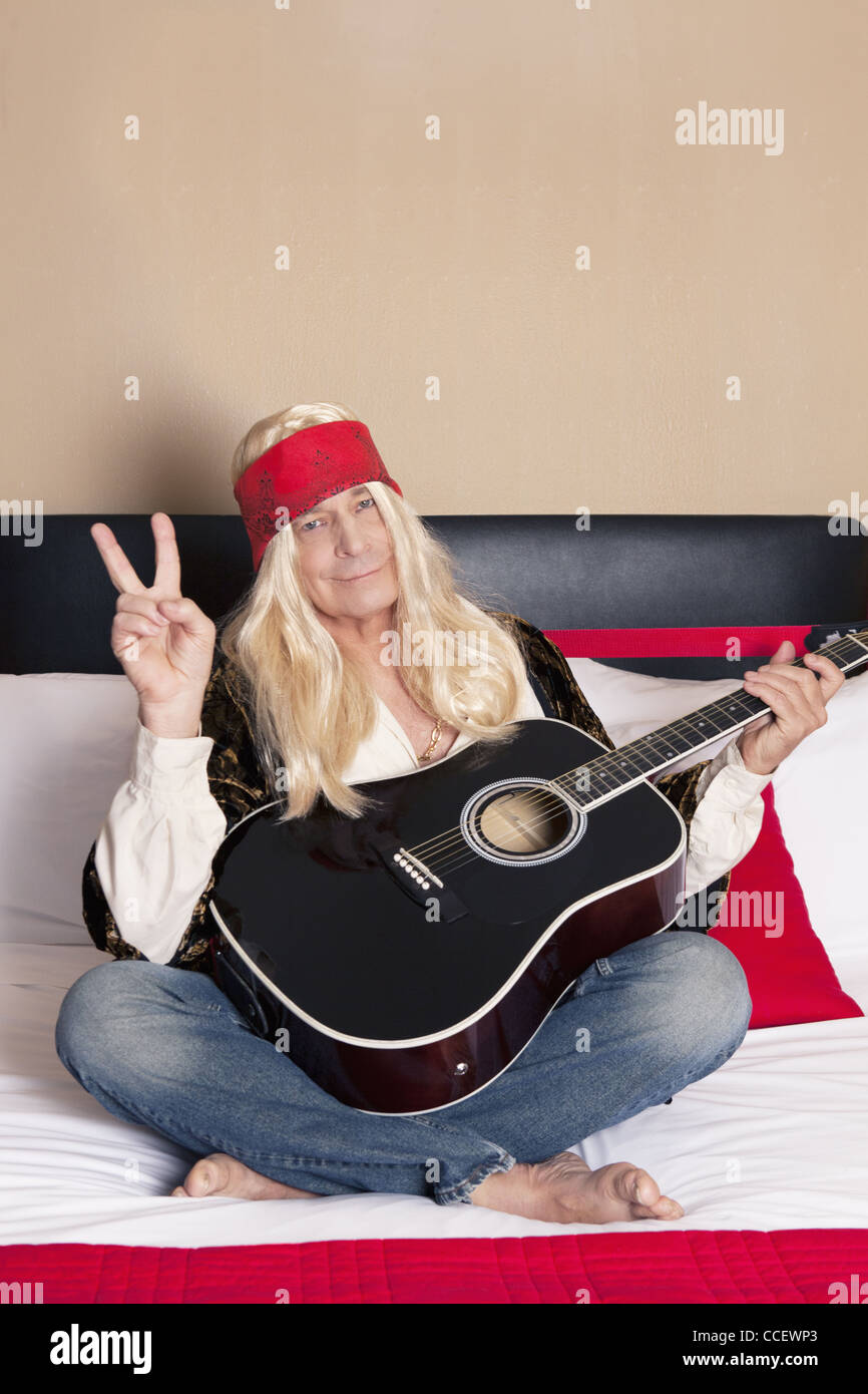 Senior man holding guitar with legs crossed Stock Photo