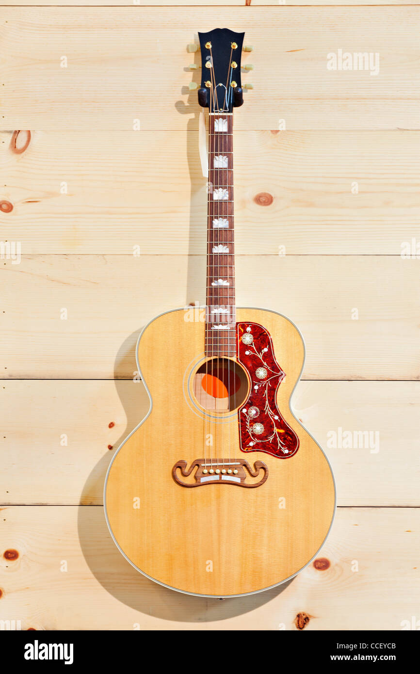 Acoustic guitar with label on a wood grain wall Stock Photo