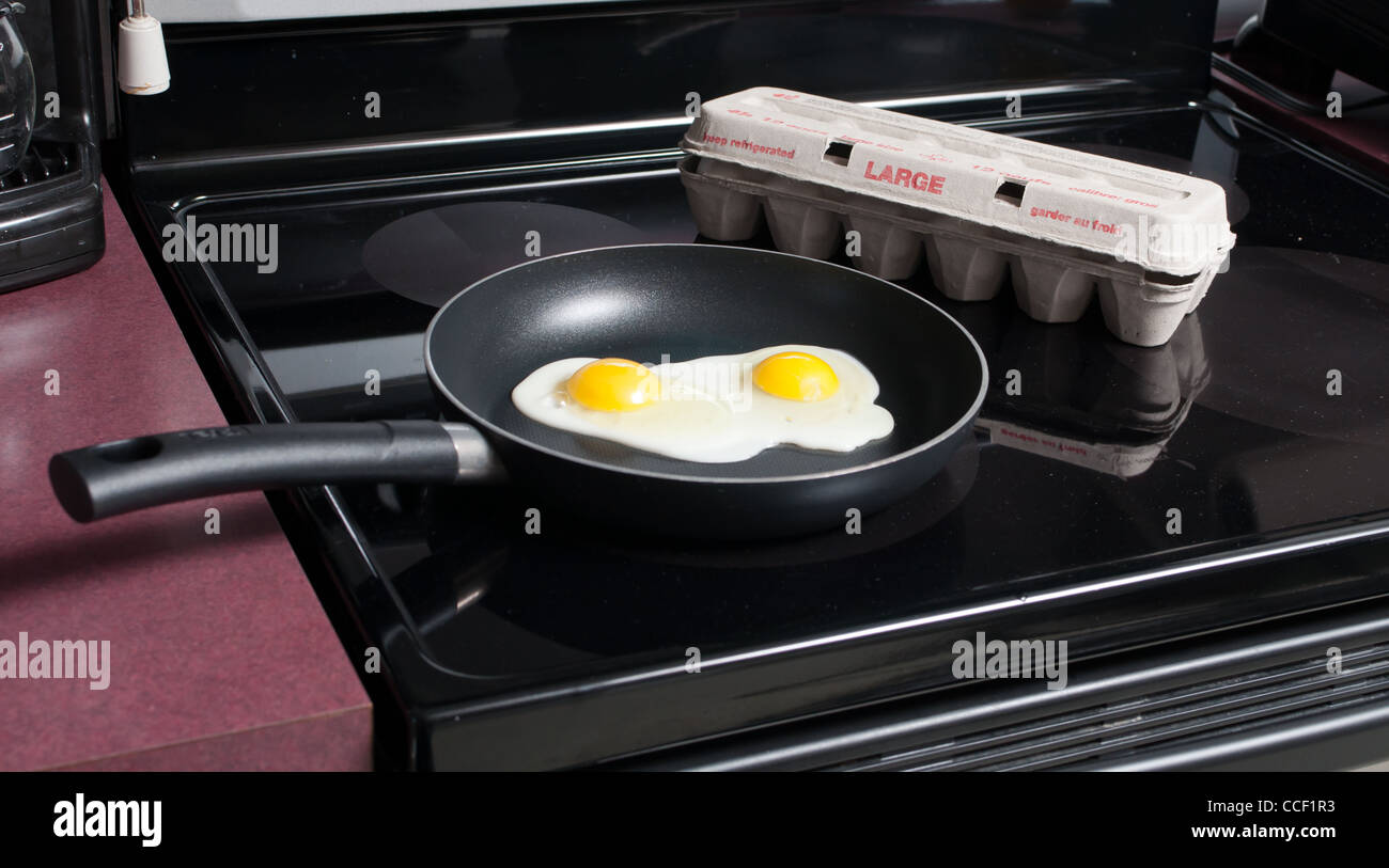 Two frying eggs cooking in a pan on the stove Stock Photo - Alamy