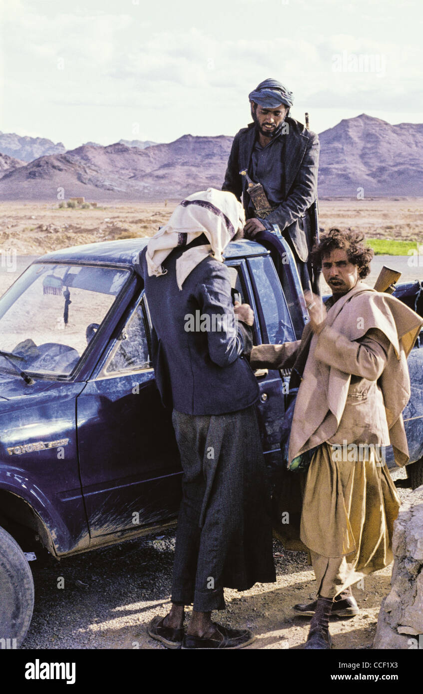 Three Yemini men standing by a pickup truck in Marib Governorate, Yemen Stock Photo